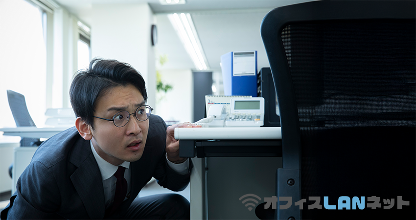 PCの暴走に驚き、机の陰に隠れる男性