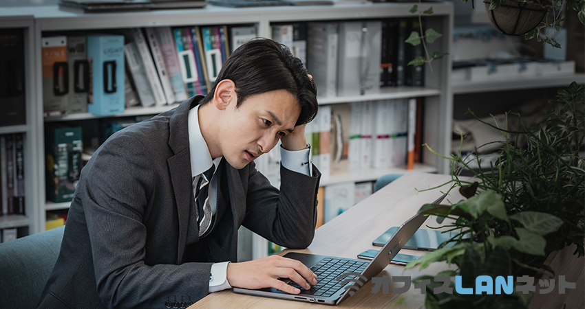 PCの前で頭を抱える男性